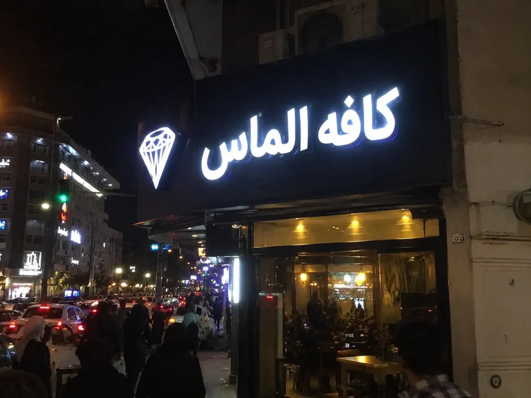 تابلو کافه الماس با حروف چلنیوم سفید در خیابان شلوغ شهری
