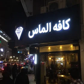 تابلو کافه الماس با حروف چلنیوم سفید در خیابان شلوغ شهری